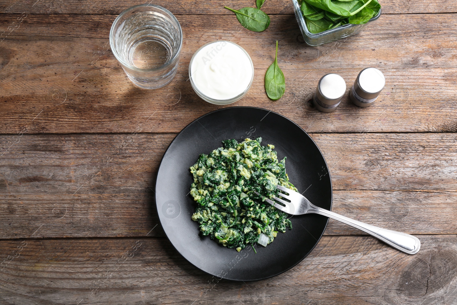 Photo of Tasty cooked spinach served on wooden table, flat lay. Healthy food