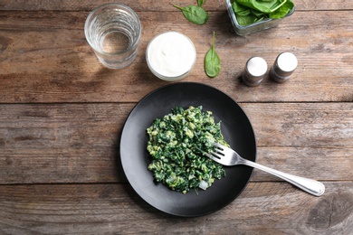 Photo of Tasty cooked spinach served on wooden table, flat lay. Healthy food