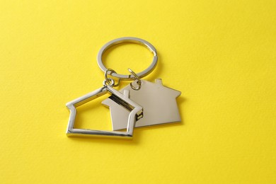 Photo of Metallic keychains in shape of houses on yellow background
