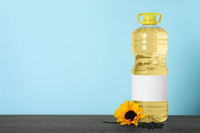 Photo of Bottle of cooking oil, sunflower and seeds on wooden table, space for text