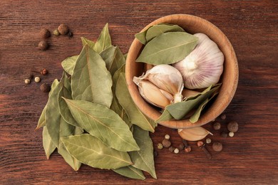 Aromatic bay leaves and spices on wooden table, flat lay