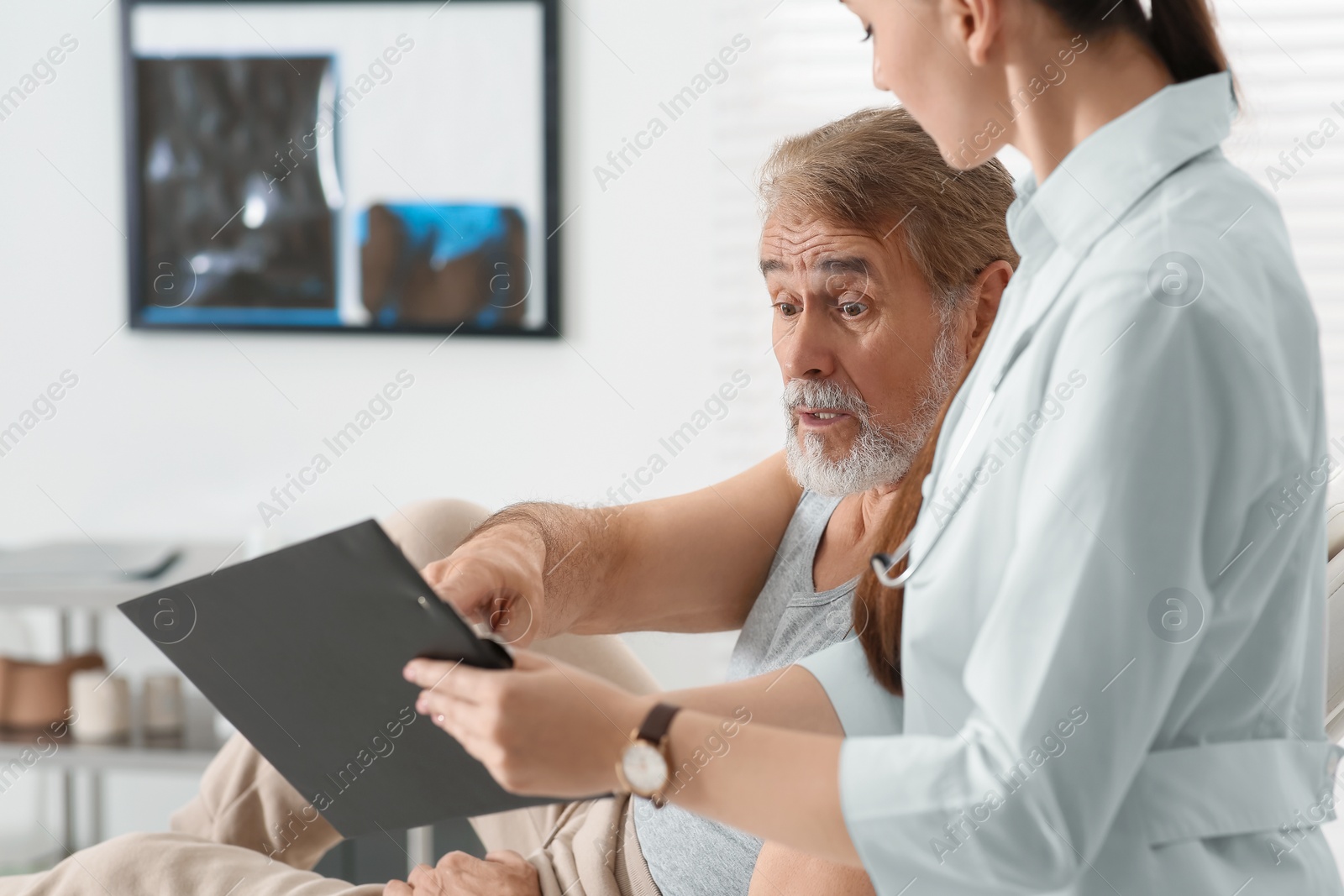 Photo of Doctor showing medical card to patient in clinic