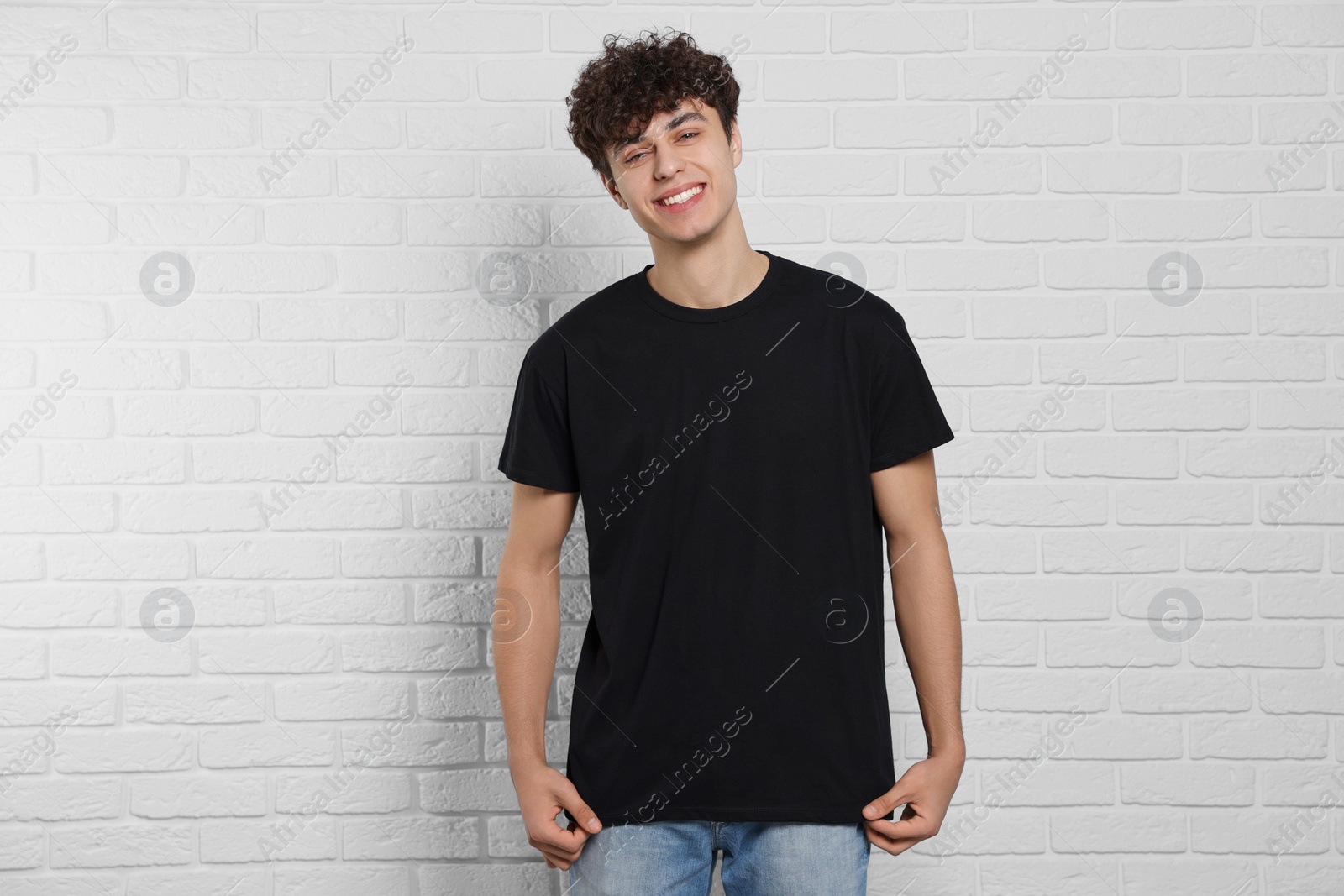 Photo of Man wearing black t-shirt near white brick wall. Mockup for design