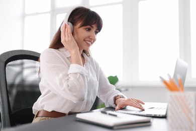 Woman in headphones watching webinar at table in office