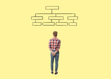 Image of Logic. Man standing in front of diagram on pale yellow background, back view