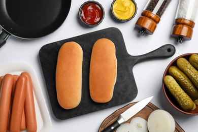 Different tasty ingredients for hot dog on white table, flat lay