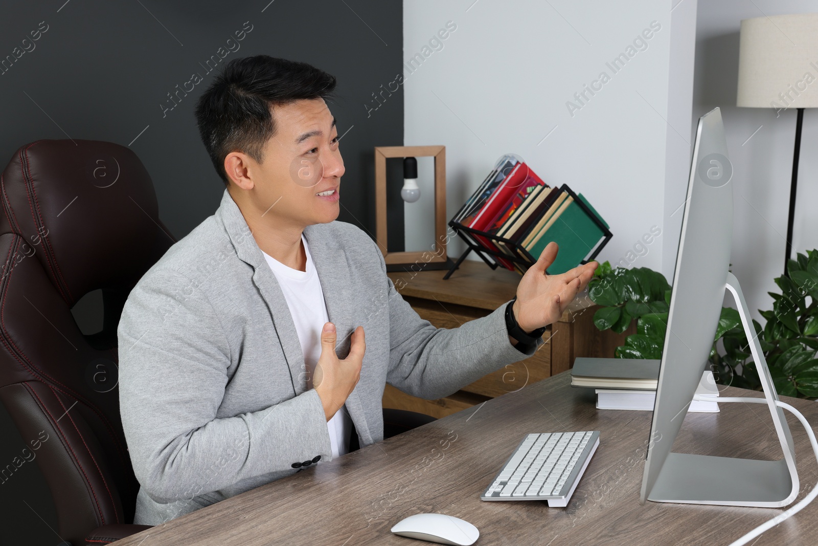 Photo of Happy boss having online meeting via computer at wooden table in modern office