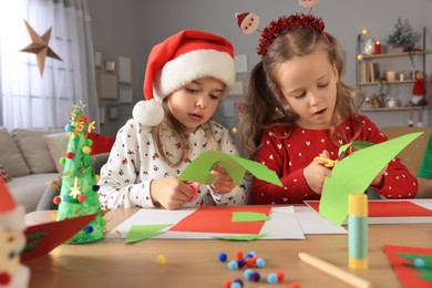 Cute little children making beautiful Christmas greeting cards at home