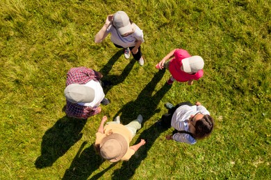 Top aerial view of people standing in circle on green grass. Drone photography
