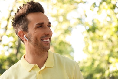 Photo of Young man with wireless earphones in park