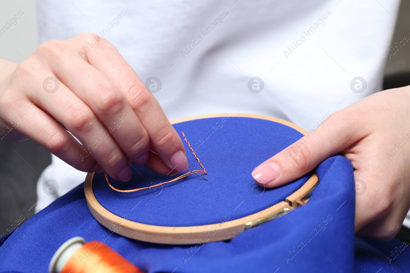 Photo of Woman with sewing needle and thread embroidering on cloth, closeup