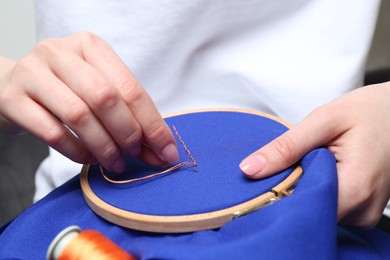 Woman with sewing needle and thread embroidering on cloth, closeup