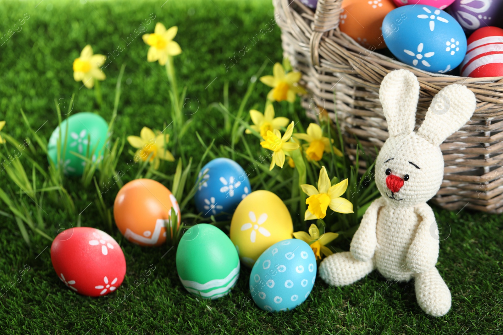 Photo of Colorful Easter eggs and toy rabbit on green grass