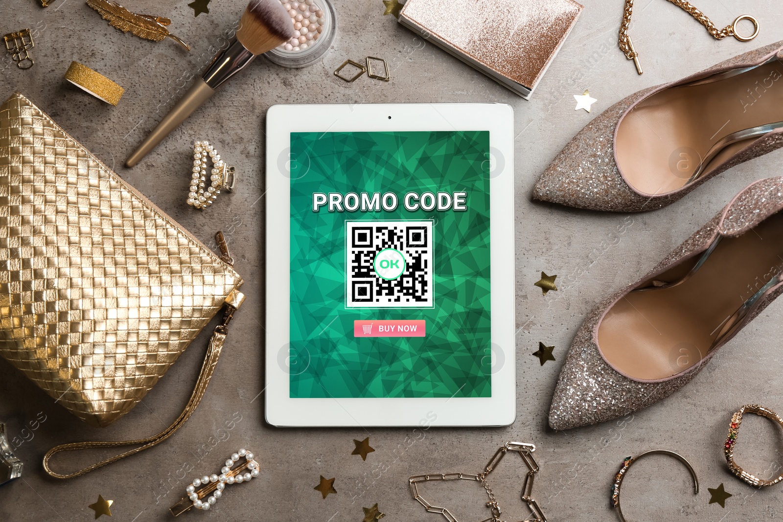 Image of Tablet with activated promo code in online shopping app and stylish accessories on grey background, flat lay