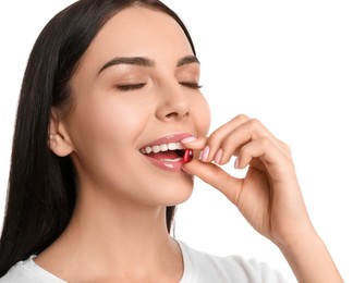 Photo of Young woman taking vitamin capsule on white background