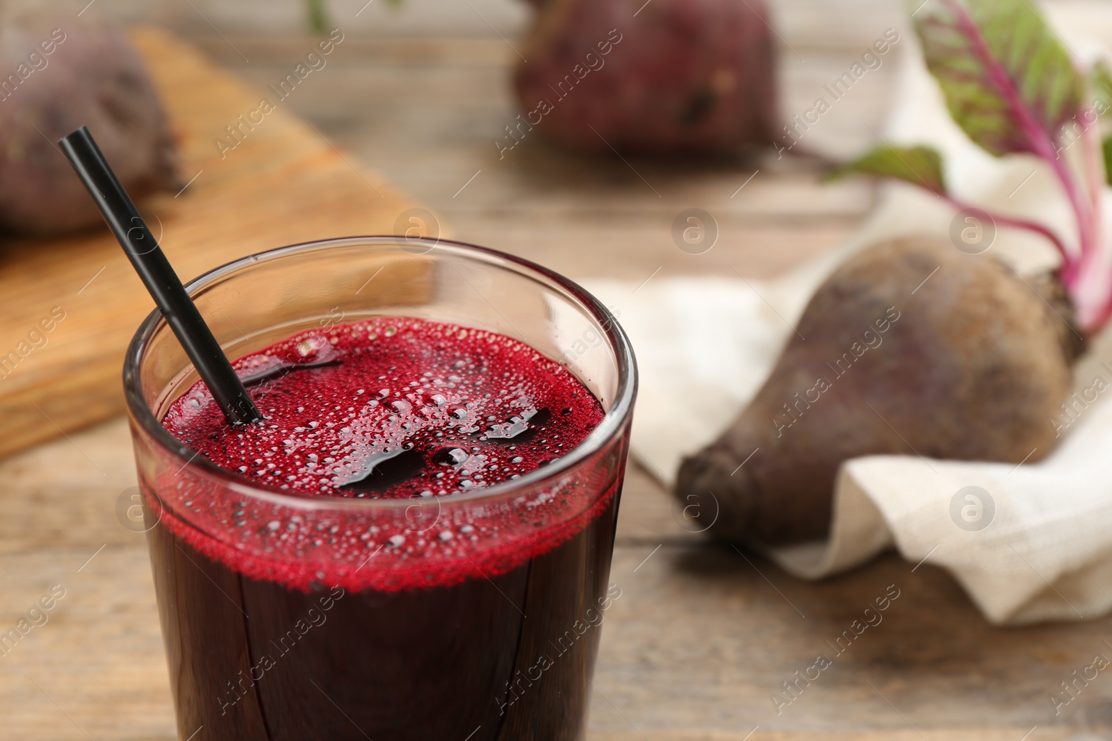 Photo of Freshly made beet juice in glass on wooden table, closeup