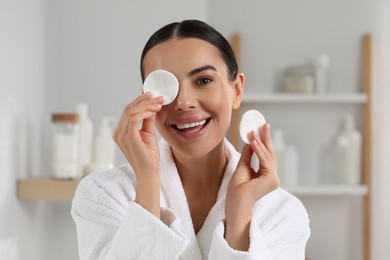 Photo of Beautiful woman removing makeup with cotton pads indoors