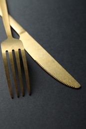 Elegant golden cutlery on black background, closeup