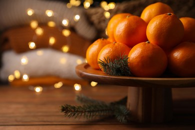 Photo of Stand with delicious ripe tangerines and fir twigs on wooden table. Space for text