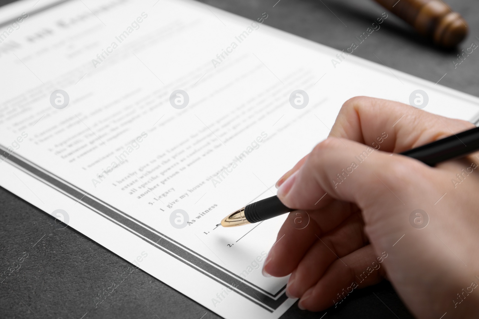 Photo of Woman signing last will and testament at grey table, closeup