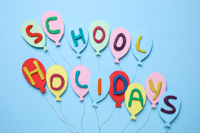 Photo of Phrase School Holidays made of modeling clay on light blue background, top view