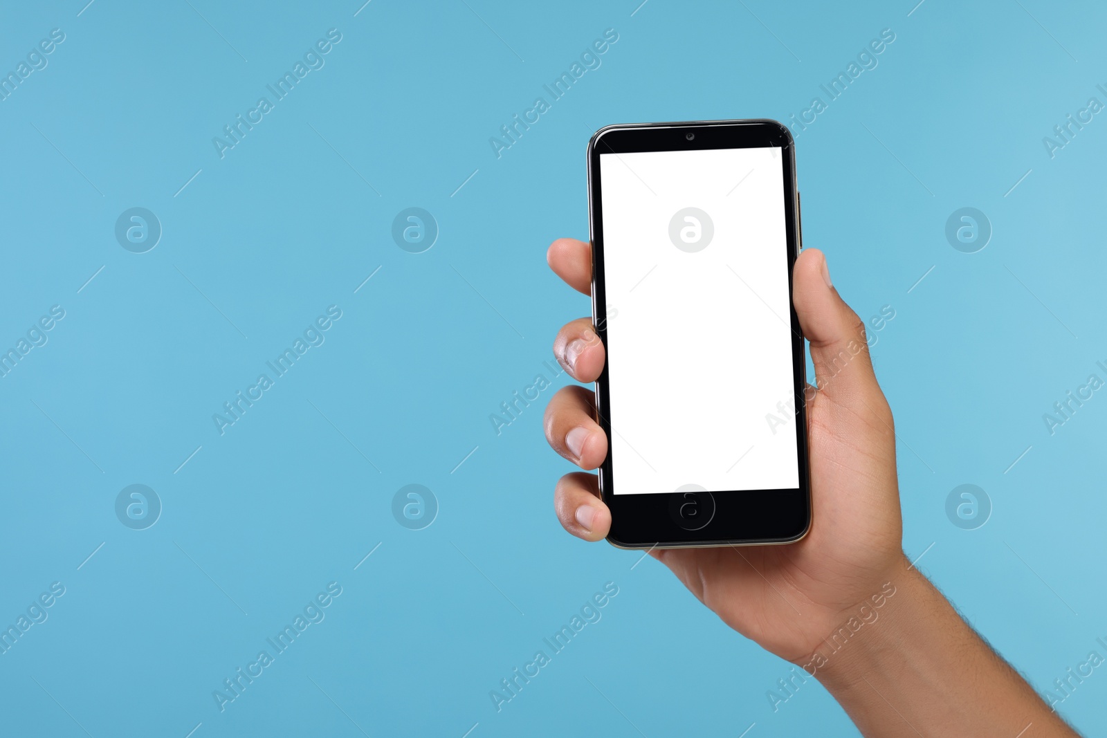 Photo of Man holding smartphone with blank screen on light blue background, closeup. Mockup for design