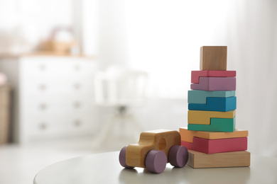 Colorful wooden blocks and car on white table in child room. Space for text