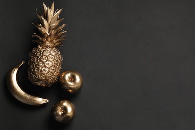 Different golden fruits on black table, flat lay. Space for text