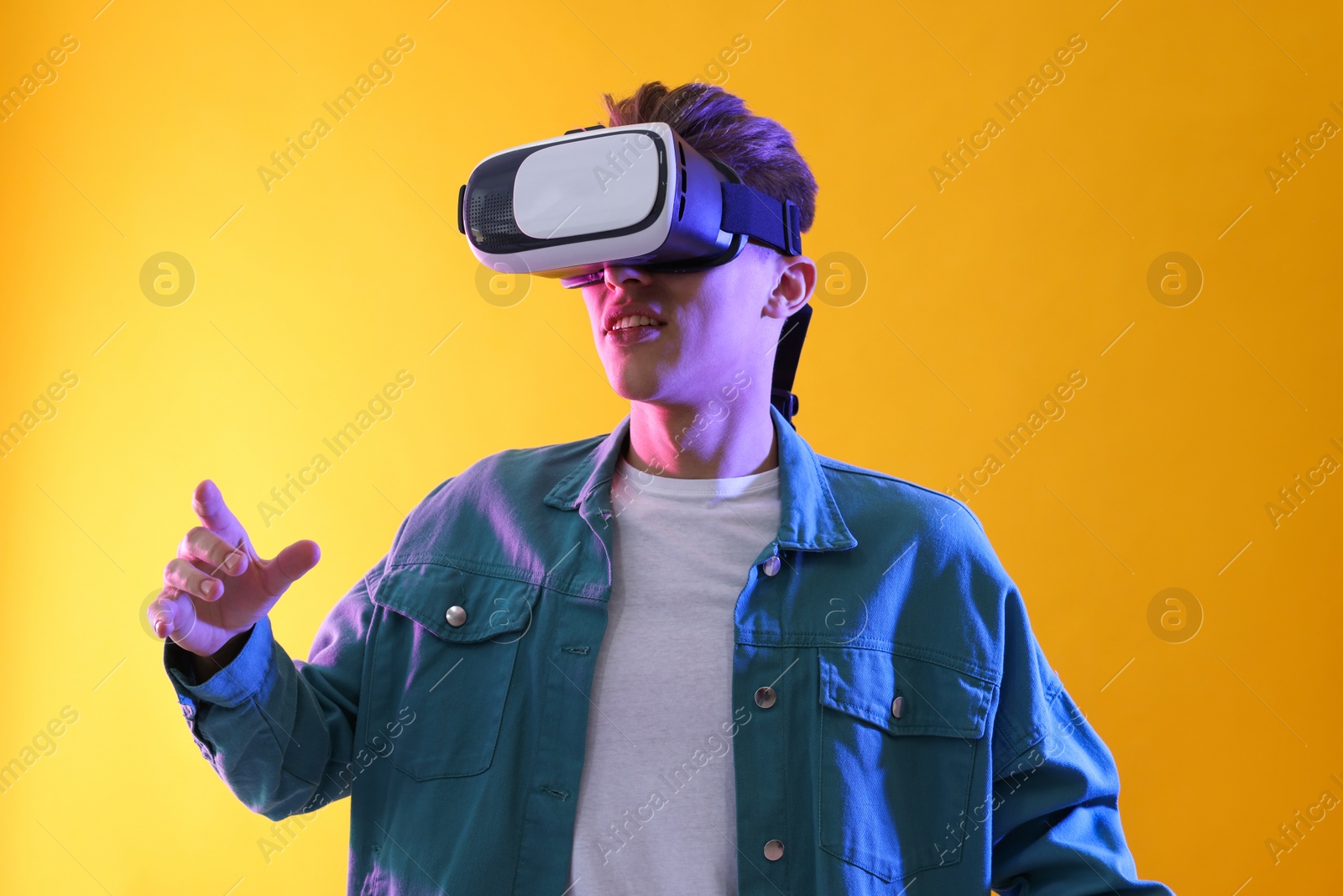 Photo of Young man with virtual reality headset on yellow background