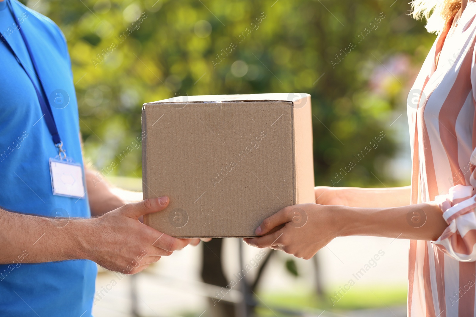 Photo of Woman receiving parcel from deliveryman on blurred background, closeup. Space for text