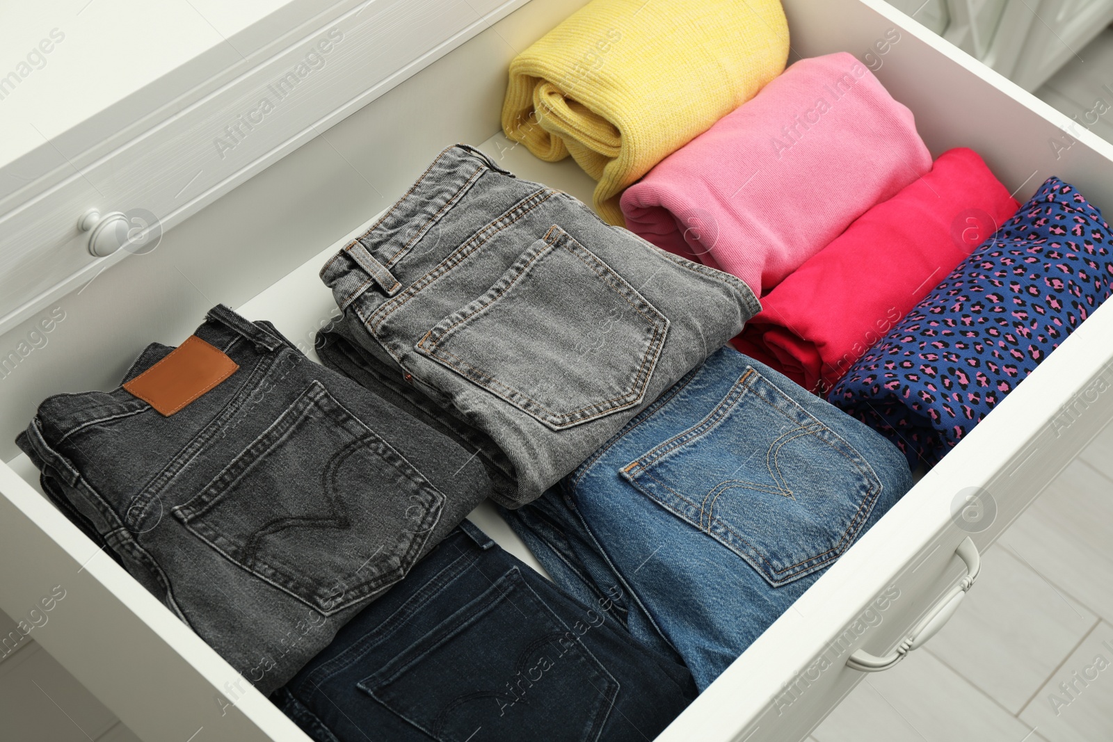 Photo of Folded clothes in open drawer. Apparel storage