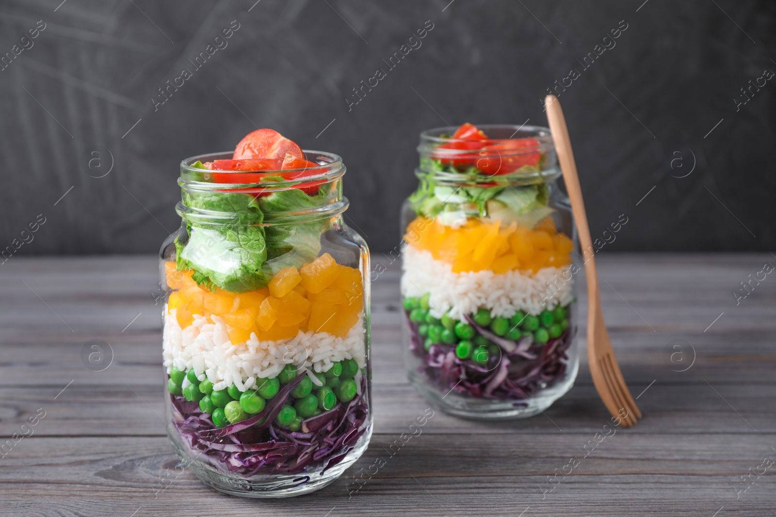 Photo of Healthy salad in glass jars on grey wooden table