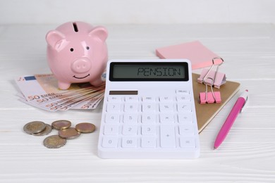 Calculator, piggy bank, money, notebook and pen on white wooden table. Retirement concept