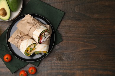 Photo of Delicious sandwich wraps with fresh vegetables, avocado and tomatoes on wooden table, flat lay. Space for text