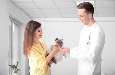 Photo of Young woman with cat and veterinarian in clinic