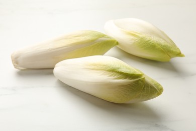 Photo of Raw ripe chicories on white marble table