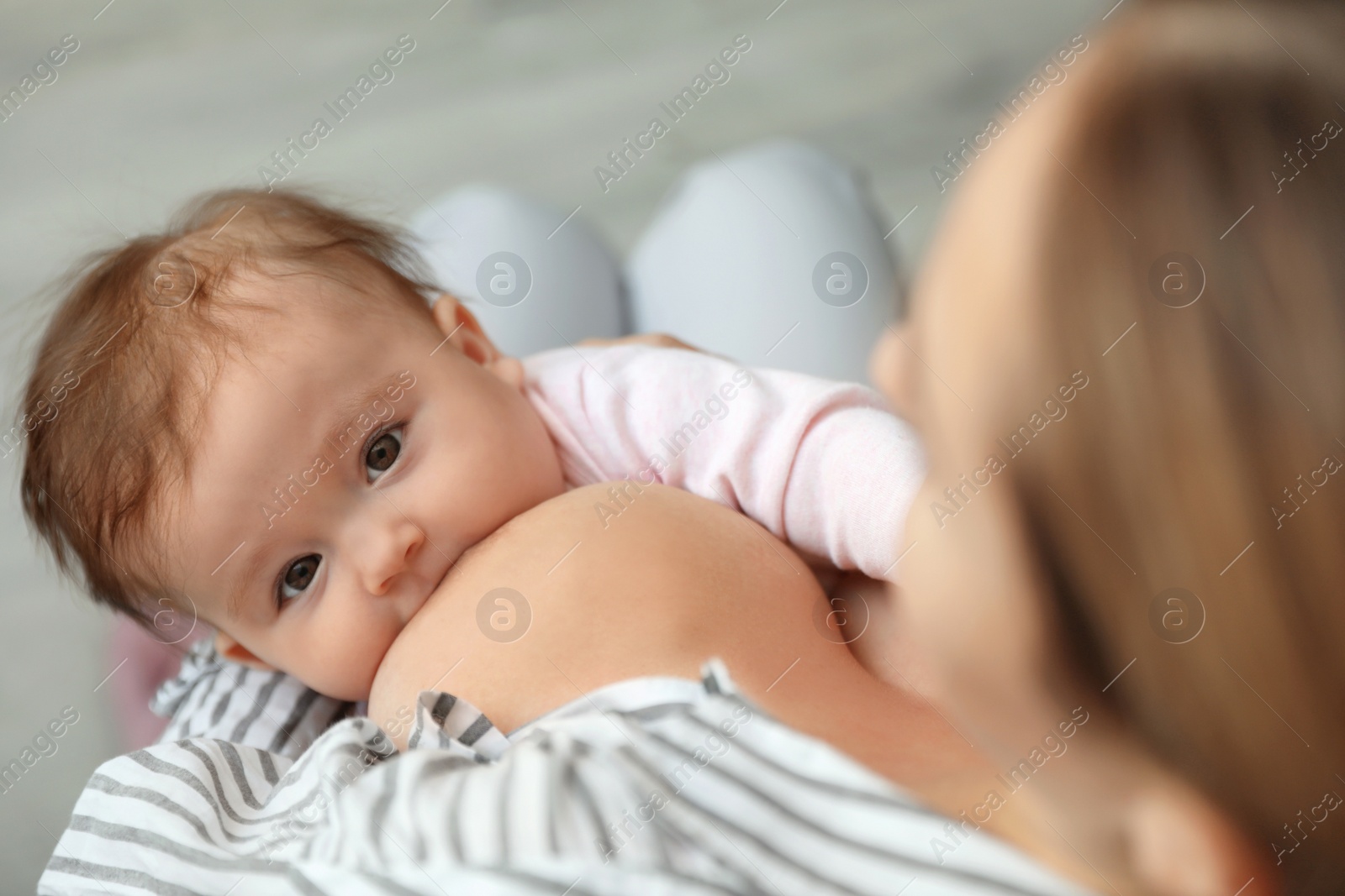 Photo of Young woman breastfeeding her baby at home, closeup