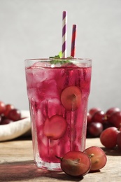 Photo of Delicious grape soda water with mint and berries on wooden table. Refreshing drink