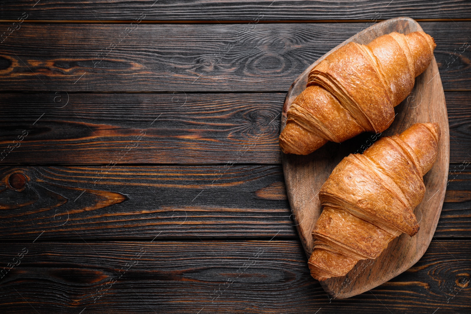 Photo of Tasty fresh croissants on wooden table, top view. Space for text