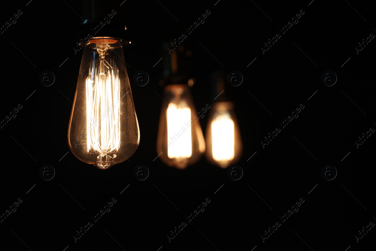 Photo of Edison light bulbs on black background, space for text