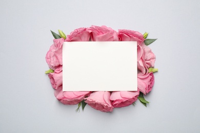 Beautiful pink Eustoma flowers and card with space for text on light grey background, flat lay
