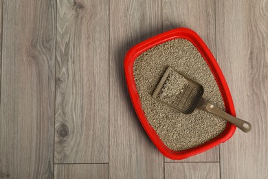 Photo of Cat tray with clumping litter and scoop on wooden floor, top view. Space for text
