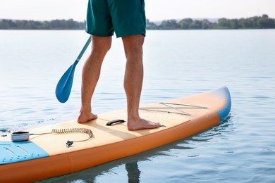 Photo of Man paddle boarding on SUP board in sea, back view. Space for text
