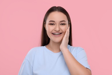 Smiling woman with dental braces on pink background