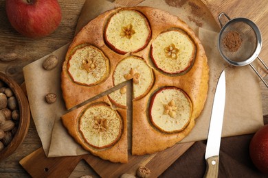 Photo of Nutmeg seeds, tasty apple pie and fresh fruits on wooden table, flat lay