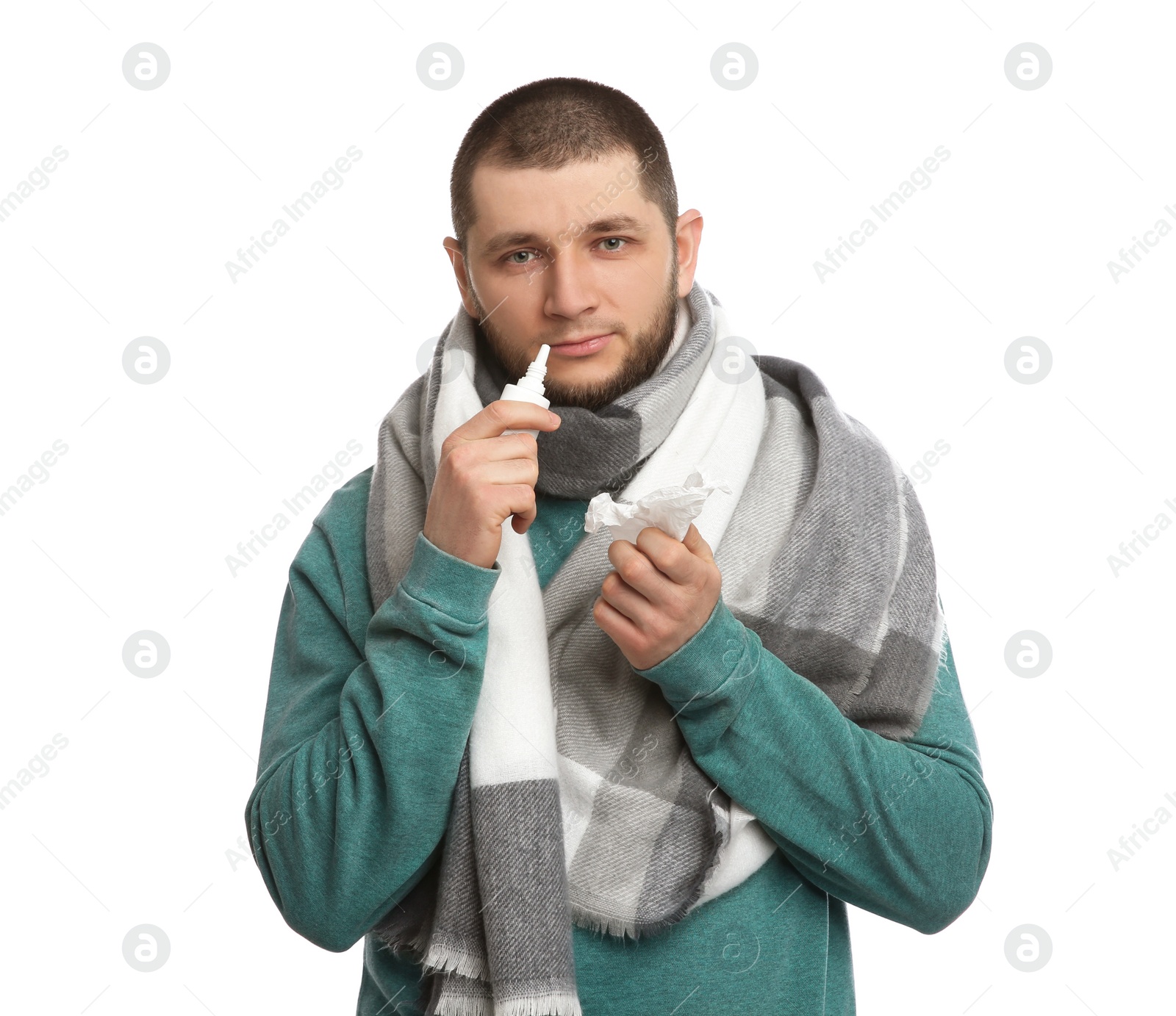 Photo of Sick man with tissue and nasal spray on white background