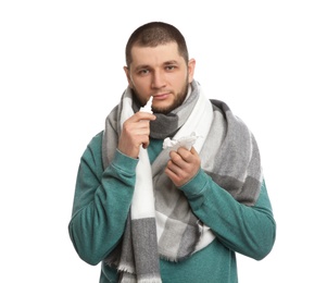 Photo of Sick man with tissue and nasal spray on white background