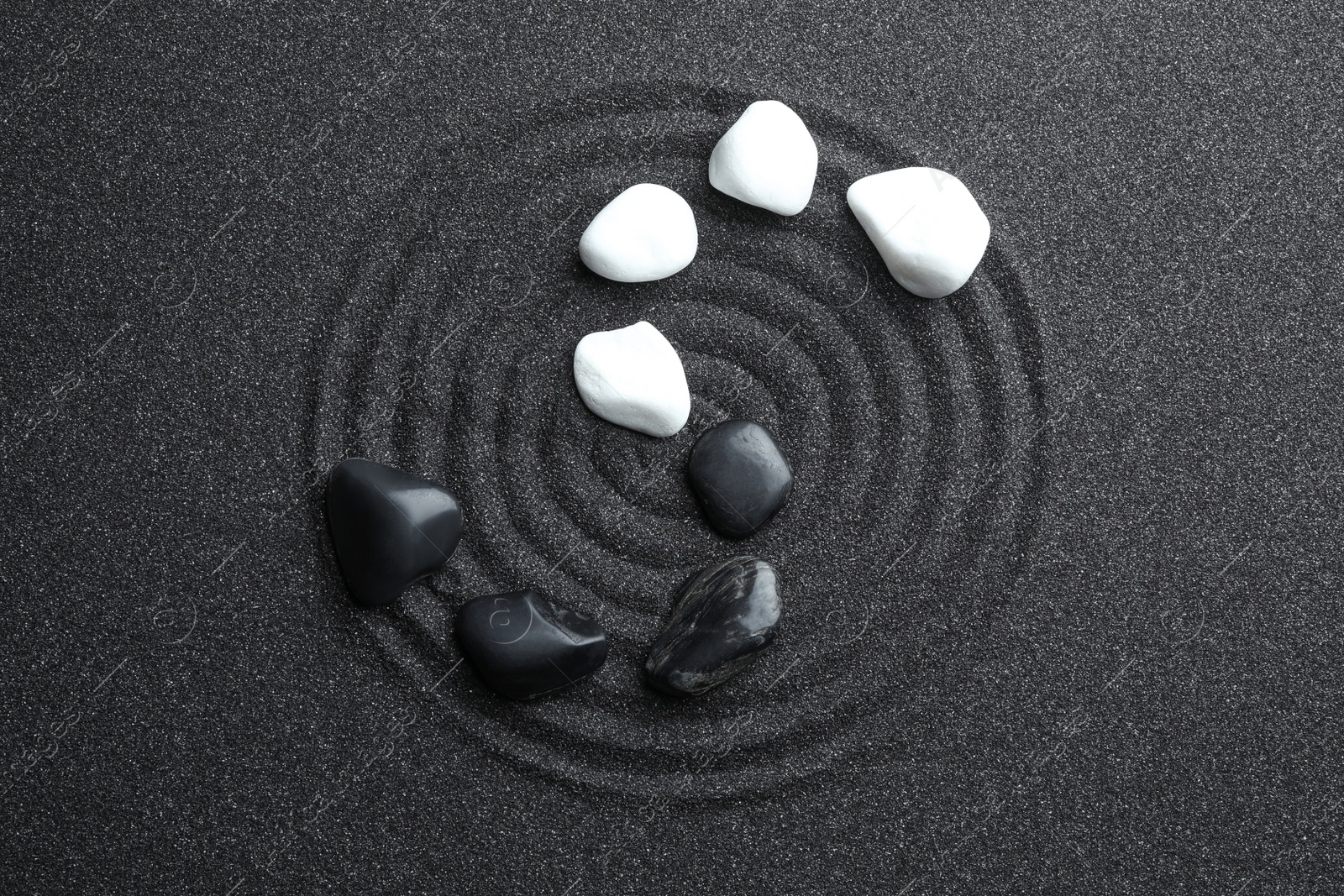Photo of Stones on black sand with beautiful pattern, flat lay. Zen and harmony