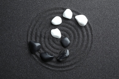 Stones on black sand with beautiful pattern, flat lay. Zen and harmony