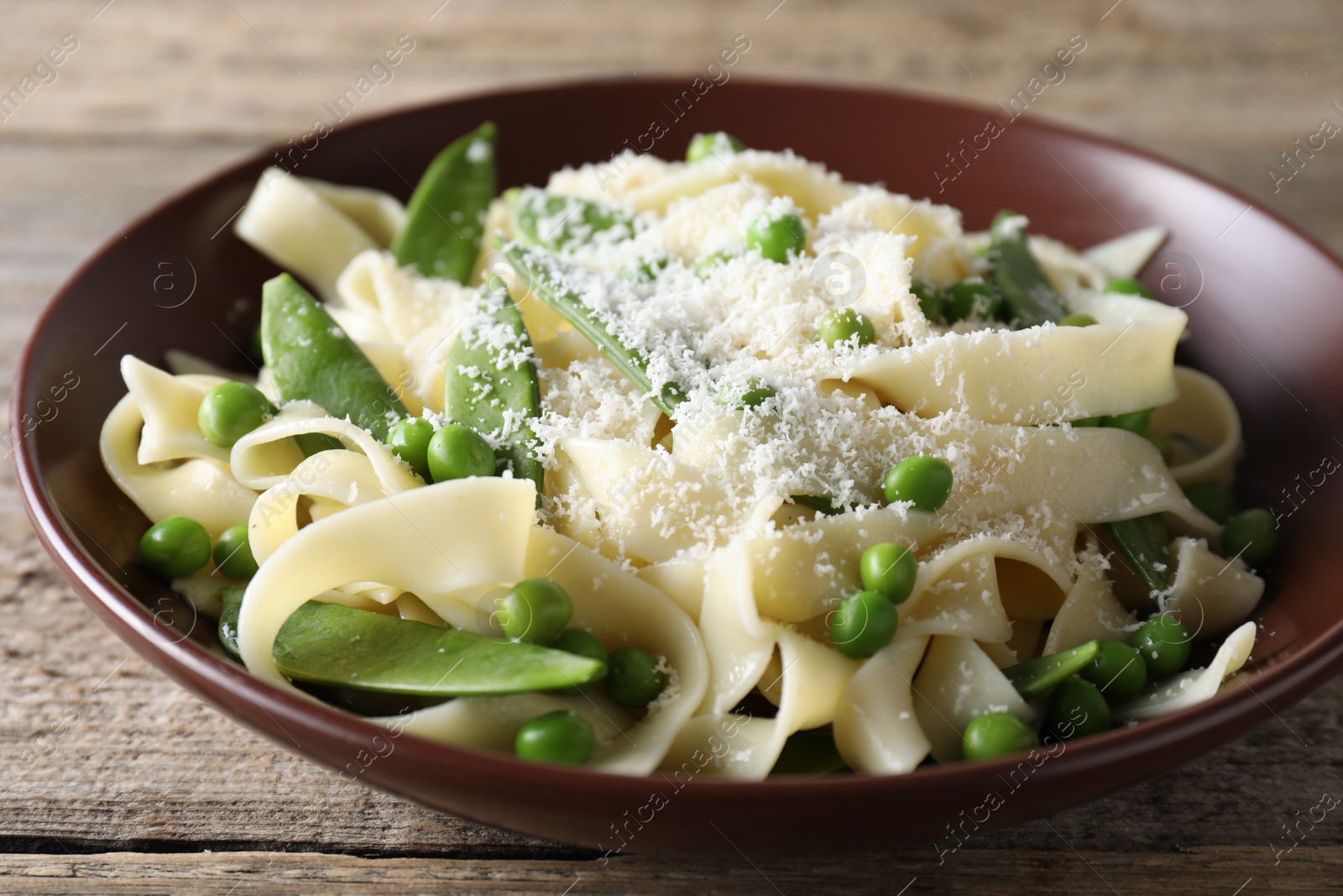 Photo of Delicious pasta with green peas and cheese on wooden table